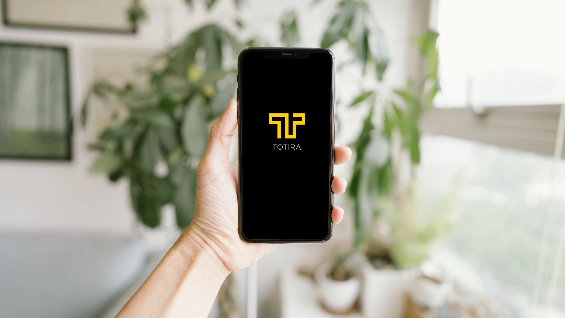 Person holding app with Totira icon on it